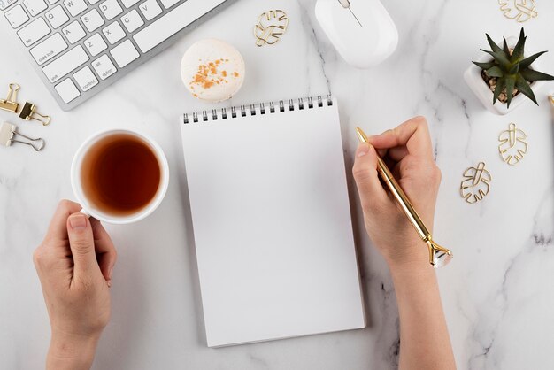 Schließen Sie herauf Hand, die goldenen Stift und Tasse hält