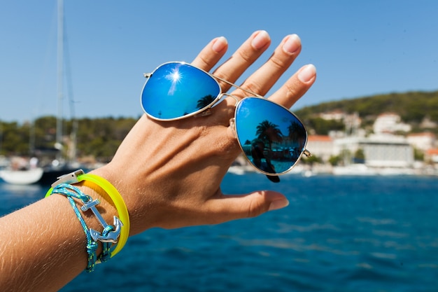 Schließen Sie herauf Hand, die stilvolle Sonnenbrille im Freien hält