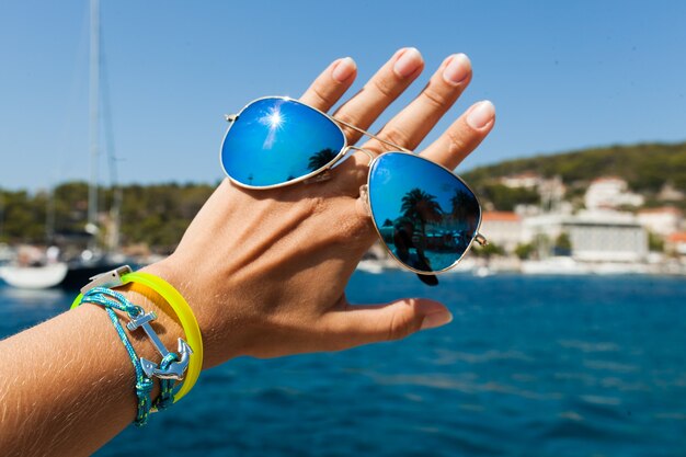 Schließen Sie herauf Hand, die stilvolle Sonnenbrille im Freien hält