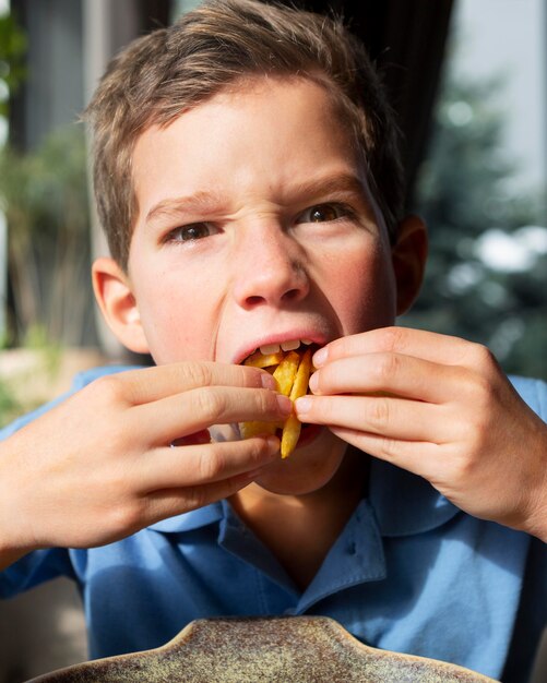 Schließen Sie herauf Junge, der Pommes frites isst