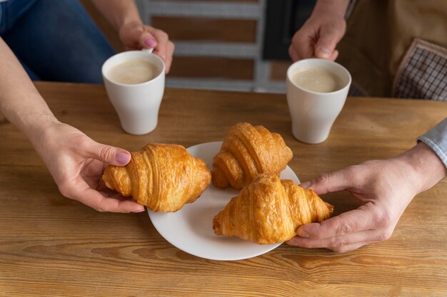 Schließen Sie herauf Leute, die Croissants und Kaffee halten