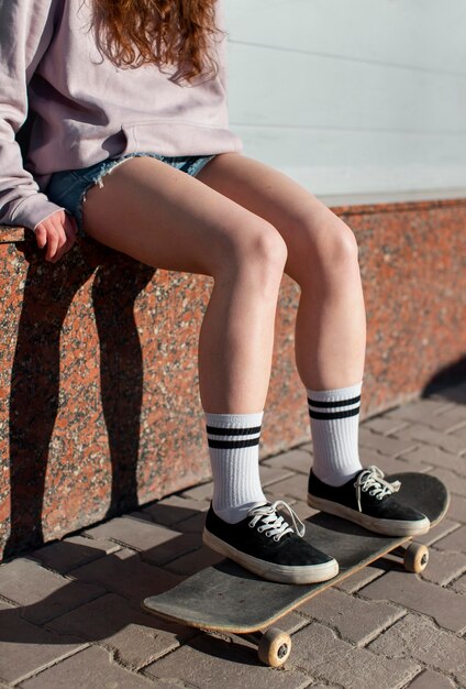 Schließen Sie herauf Mädchen, das auf Skateboard sitzt
