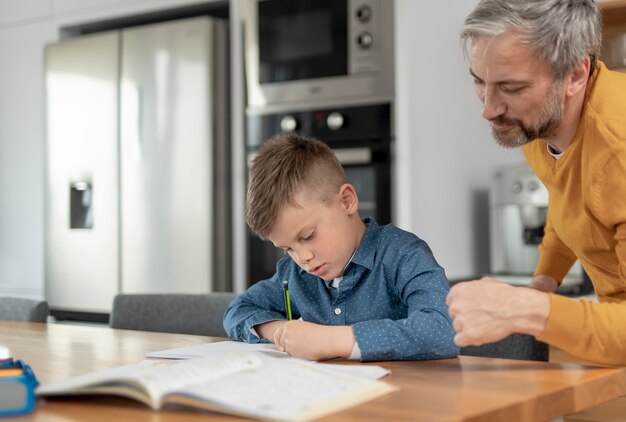 Schließen Sie herauf Mann, der Kind mit Hausaufgaben hilft