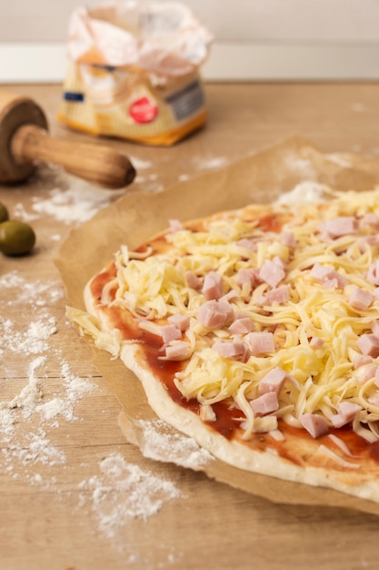 Schließen Sie herauf Pizzateig mit Tomatensauce Mozzarella und Schinken