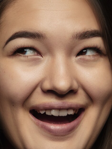 Schließen Sie herauf Porträt der jungen und emotionalen chinesischen Frau. Hochdetailliertes Fotoshot eines weiblichen Models mit gepflegter Haut und strahlendem Gesichtsausdruck. Konzept menschlicher Emotionen. Aufschauen, lächeln.