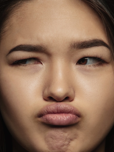 Schließen Sie herauf Porträt der jungen und emotionalen chinesischen Frau. Hochdetailliertes Fotoshot eines weiblichen Models mit gepflegter Haut und strahlendem Gesichtsausdruck. Konzept menschlicher Emotionen. Denken, zur Seite schauen.