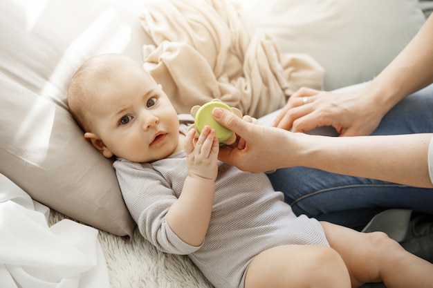 Schließen Sie herauf Porträt der niedlichen kleinen Babyfrau, während Sie Spielzeug mit ihrer jungen schönen Mutter spielen. Familien-, Lebensstil- und Mutterschaftskonzept.