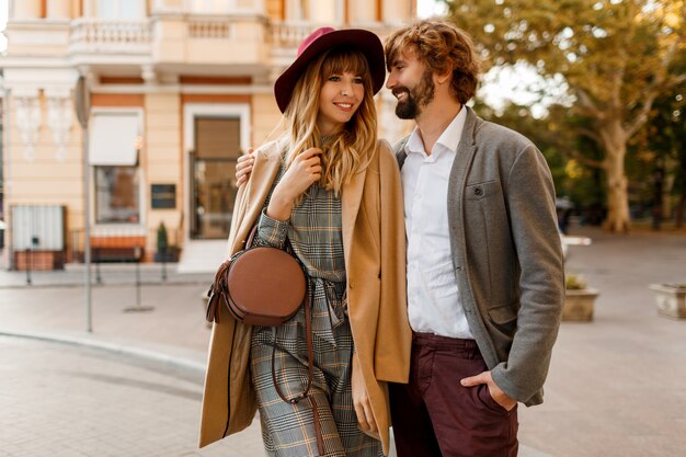 Schließen Sie herauf Porträt des erstaunlichen stilvollen Paares in der Liebe, die romantische Ferien in der europäischen Stadt verbringt. Hübsche blonde Frau im Hut und im lässigen Kleid lächelnd und auf ihrem gutaussehenden Mann mit Bart schauend.