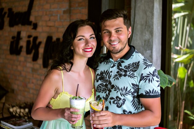 Schließen Sie herauf Porträt des glücklichen jungen hübschen Paares, das Jubel vor der Kamera, tropische Partystimmung macht, Spaß zusammen hat, im Café aufwirft, Sommerzeit entspannen.