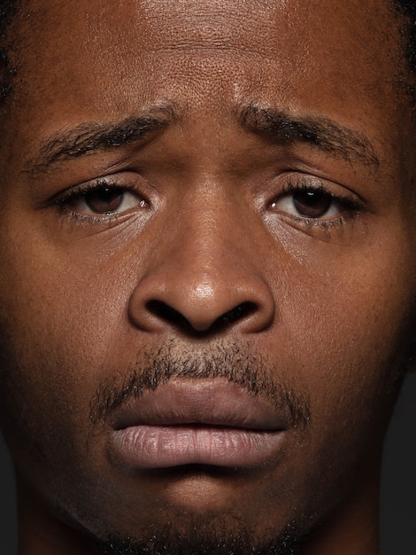 Schließen Sie herauf Porträt des jungen und emotionalen afroamerikanischen Mannes. Hochdetailliertes Foto des männlichen Models mit gepflegter Haut und Gesichtsausdruck. Konzept menschlicher Emotionen. Verärgert, traurig, demotiviert.