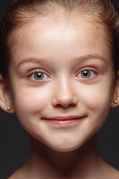 Schließen Sie herauf Porträt des kleinen und emotionalen kaukasischen Mädchens. Hochdetailliertes Fotoshot eines weiblichen Models mit gepflegter Haut und strahlendem Gesichtsausdruck. Konzept menschlicher Emotionen. Kamera betrachten.