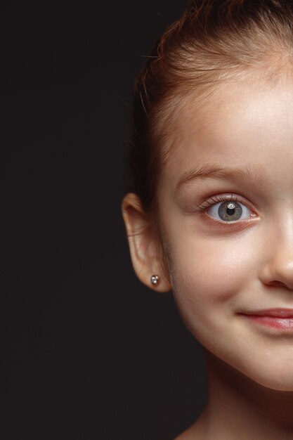 Schließen Sie herauf Porträt des kleinen und emotionalen kaukasischen Mädchens. Hochdetailliertes Fotoshot eines weiblichen Models mit gepflegter Haut und strahlendem Gesichtsausdruck. Konzept menschlicher Emotionen. Ruhiges Lächeln.
