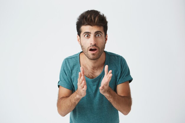 Schließen Sie herauf Porträt des reifen italienischen Kerls im lässigen blauen T-Shirt, Händchen haltend, gefroren in einer Pose in Erwartung während des Hockeyspiels. Körpersprache.