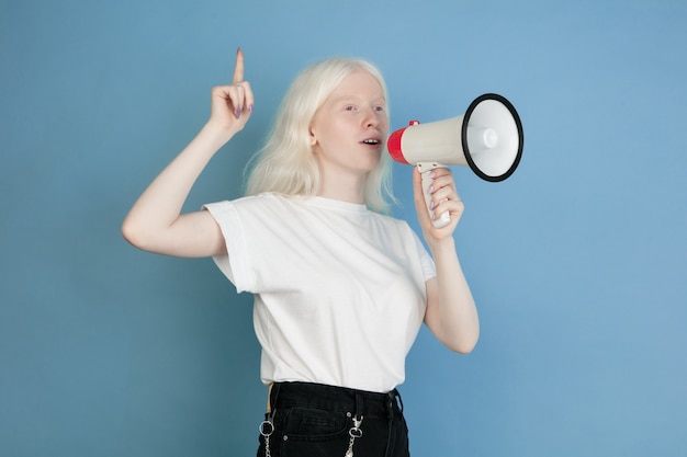 Schließen Sie herauf Porträt des schönen kaukasischen Albino-Mädchens auf Blau. Blondes weibliches Modell mit stilvollem Blick. Konzept von Gesichtsausdruck, menschlichen Emotionen, Kindheit, Werbung, Verkauf, Vielfalt.