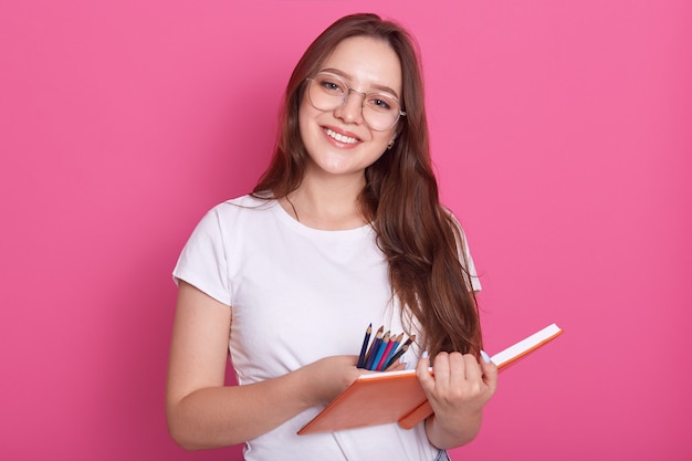 Schließen Sie herauf Porträt des schönen Studentenmädchens, das bereit ist, Notizen im Heft zu machen, angenehmes Aussehen