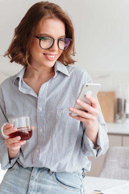 Schließen Sie herauf Porträt einer lächelnden Frau unter Verwendung des Mobiltelefons