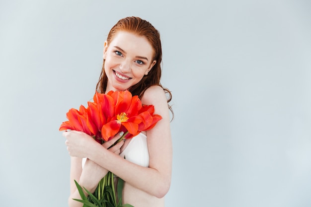 Schließen Sie herauf Porträt einer rothaarigen Frau, die Tulpenblumen hält
