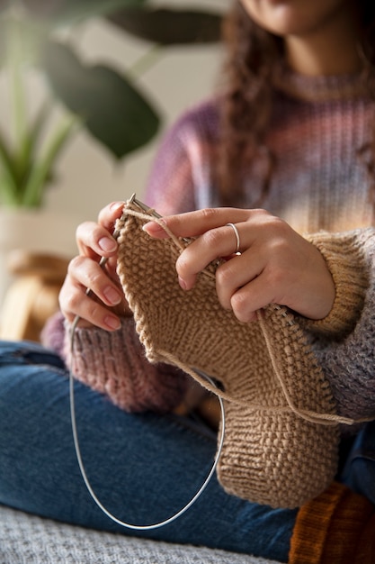 Schließen sie herauf undeutliche frau, die zu hause strickt