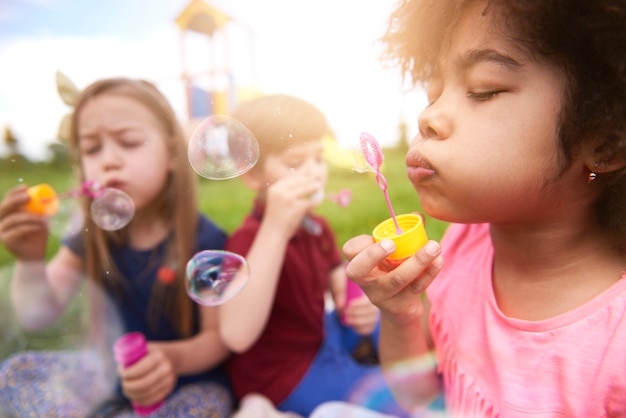 Schließen Sie oben auf glücklichen Kindern, die mit Seifenblasen spielen