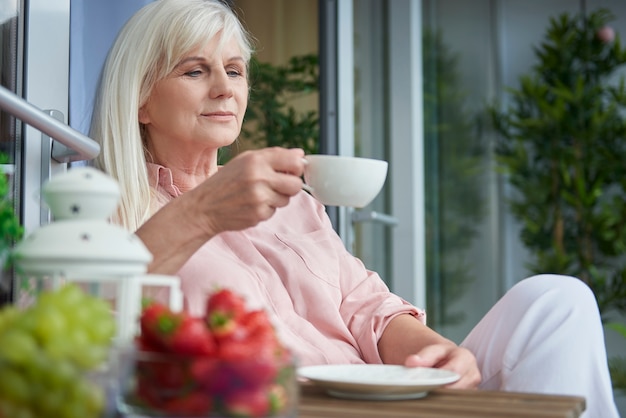 Schließen Sie oben auf reife Frau, die guten Kaffee auf dem Balkon genießt