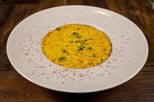 Schließen Sie oben und über einem Teller Risotto mit Safran, weißer Teller auf einem rustikalen Tisch