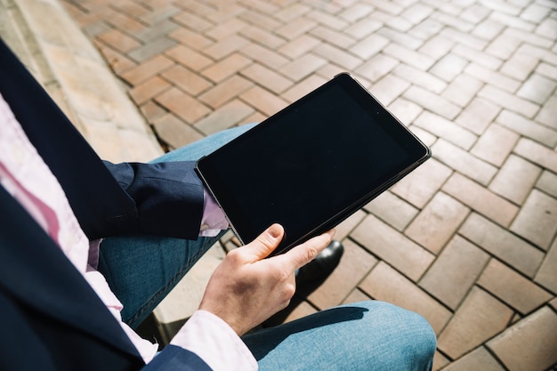 Schließen Sie oben vom Geschäftsmann unter Verwendung der Tablette draußen