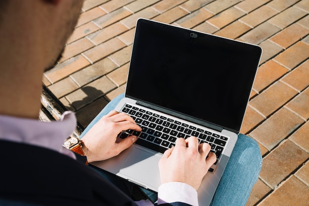 Schließen Sie oben vom Geschäftsmann unter Verwendung des Laptops draußen