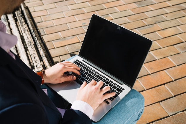 Schließen Sie oben vom Geschäftsmann unter Verwendung des Laptops draußen