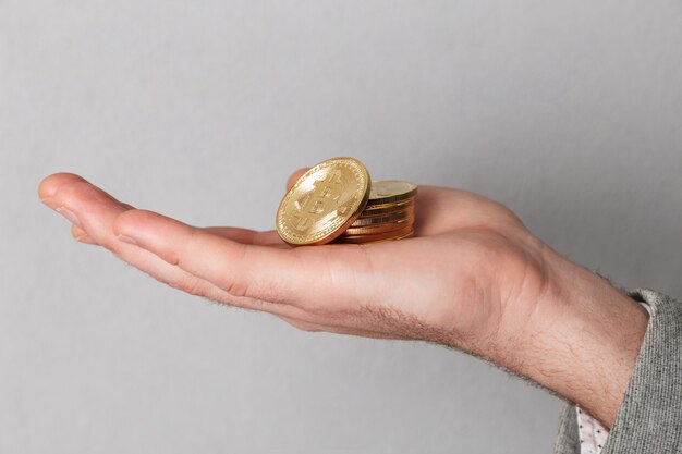 Schließen Sie oben vom Mann, der Stapel goldene bitcoins zeigt