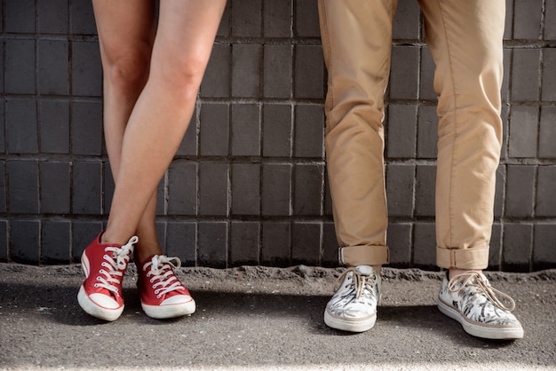 Schließen sie oben von den beinen des paares in keds über der grauen wand.