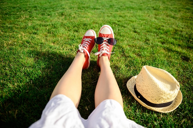 Kostenloses Foto schließen sie oben von den beinen in den roten keds, die auf gras liegen.