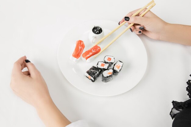 Schließen Sie oben von den weiblichen Händen mit Plastiksushi, Öko-Konzept. Organische Welt verlieren.