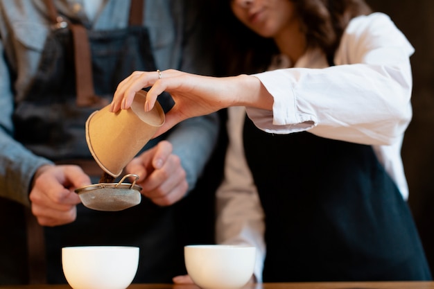 Schließen Sie oben von der Frau, die Kaffee in der Schale siebt