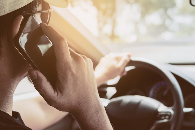 Schließen Sie oben von einem Mann, der gefährlich Auto während der Verwendung des Handys fährt