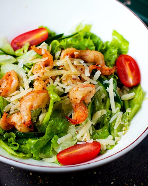 Schließen Sie oben von einer Schüssel des gebratenen Garnelensalats mit geriebenem Salatkirschtomatenkäse