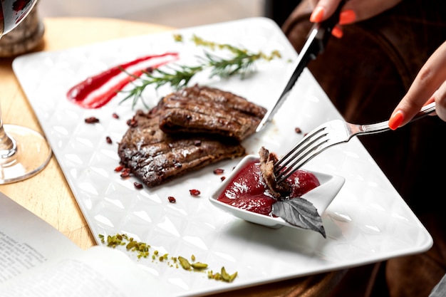 Kostenloses Foto schließen sie oben von frau, die steakstück in saure soße eintaucht