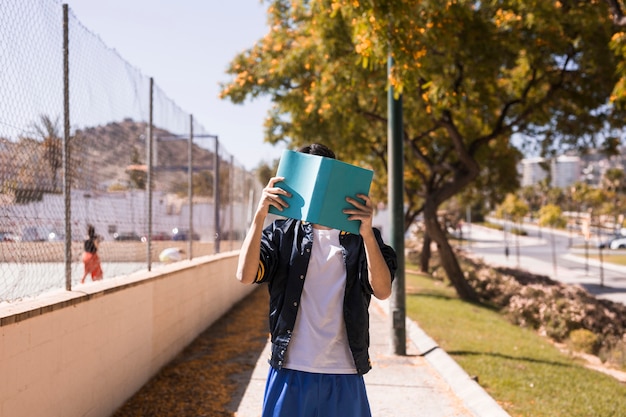 Schließendes Gesicht des Jugendlichen durch Buch