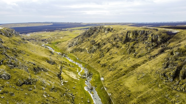 Schlucht in den Hügeln von Moldawien mit schwimmendem Fluss, bewölktem Himmel, Felder auf dem Hintergrund