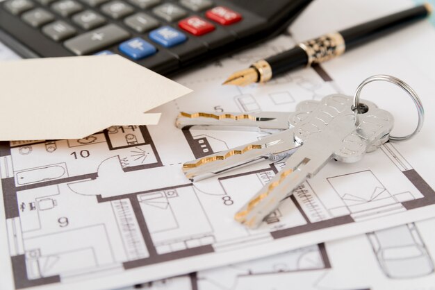 Schlüssel; Füller; Hauspapier ausgeschnitten und Taschenrechner auf architektonischen Plänen