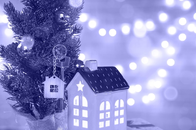 Schlüssel zum haus mit einem schlüsselanhänger auf einem weihnachtlich dekorierten tisch. ein geschenk für neujahr, weihnachten. bauen, entwerfen, projektieren, in ein neues haus umziehen, hypotheken, miete und kauf von immobilien. platz kopieren