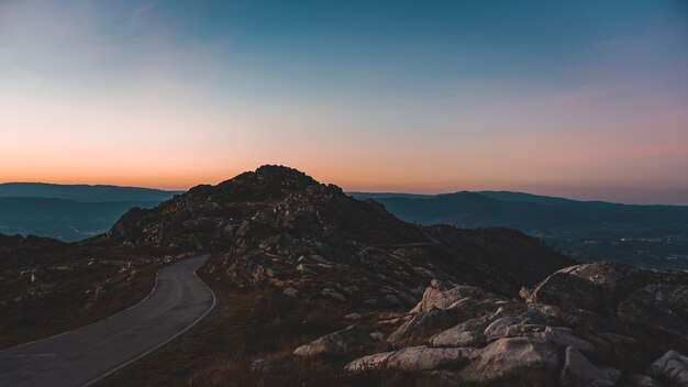 Schmale Straße, die zu einer felsigen Höhle unter dem schönen Sonnenuntergangshimmel führt