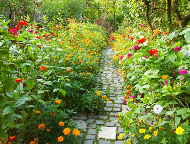 Schmaler Weg in einem Garten, umgeben von vielen bunten Blumen