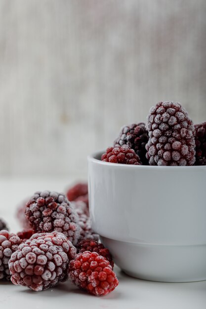 Schneebedeckte Brombeeren in einer Seitenansicht der weißen Tasse