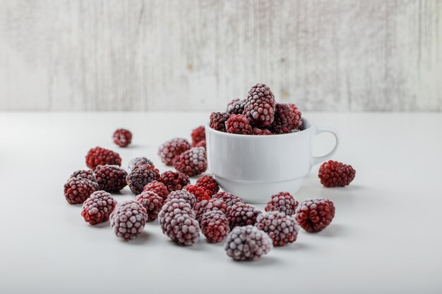 Schneebedeckte Brombeeren in einer Seitenansicht der weißen Tasse