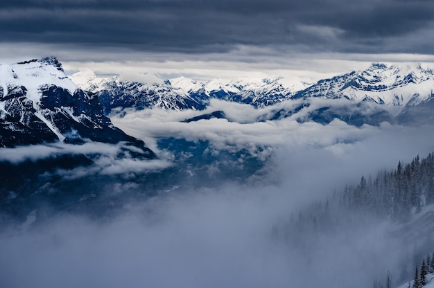 Kostenloses Foto schneebedeckte gipfel der felsigen berge unter dem bewölkten himmel