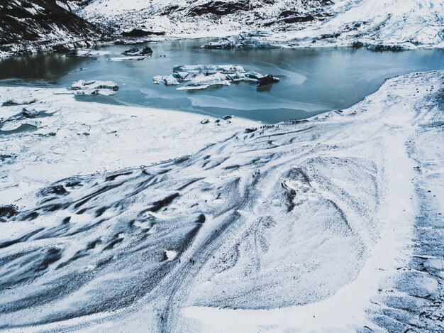 Schneeweiße Wanderwege in den schroffen Bergen mit einem gefrorenen eisigen See