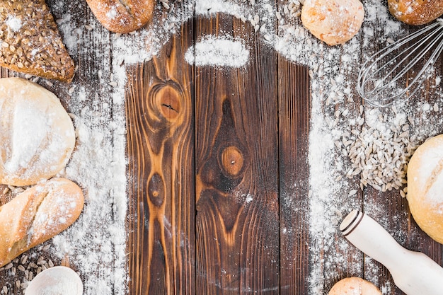 Schneidebrettrahmen mit ausgebreitetem Mehl und umgebenen Brotlaiben