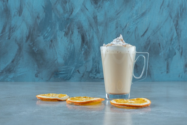 Schneidet Zitrone neben einer Tasse Cappuccino auf dem blauen Tisch.