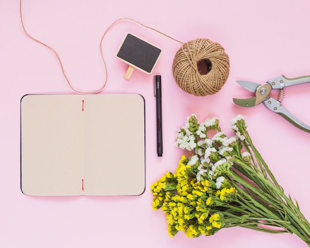 Kostenloses Foto schnurspule; stift; etikette; tagebuch; blumen und gartenschere vor rosa hintergrund