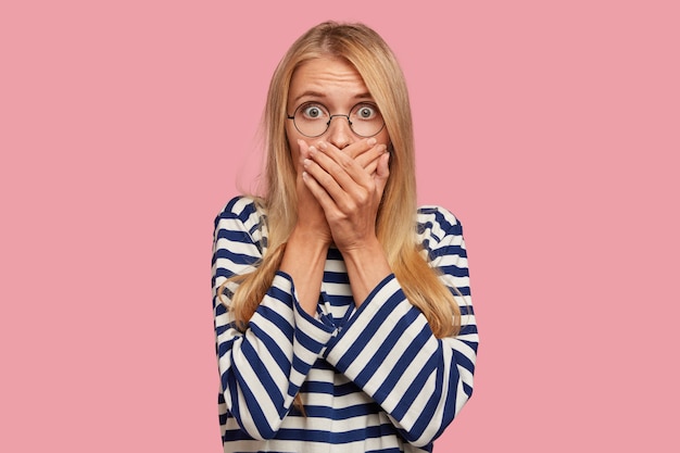 Kostenloses Foto schockierte blonde frau posiert gegen die rosa wand